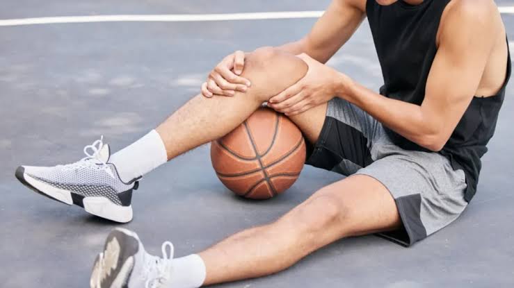 sports-injury-physical-therapy-with-basketball-player-using-ball-under-knee